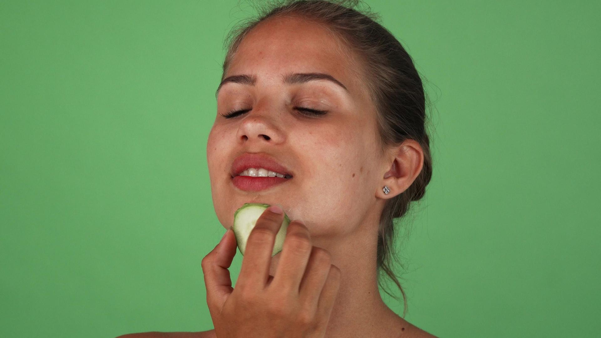 一个迷人的女人用一小块黄瓜摩擦她的脸视频的预览图