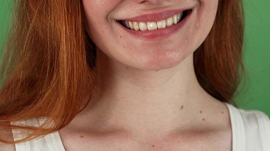 红发红发的女人在绿色染色食品的背景下开心地微笑视频的预览图