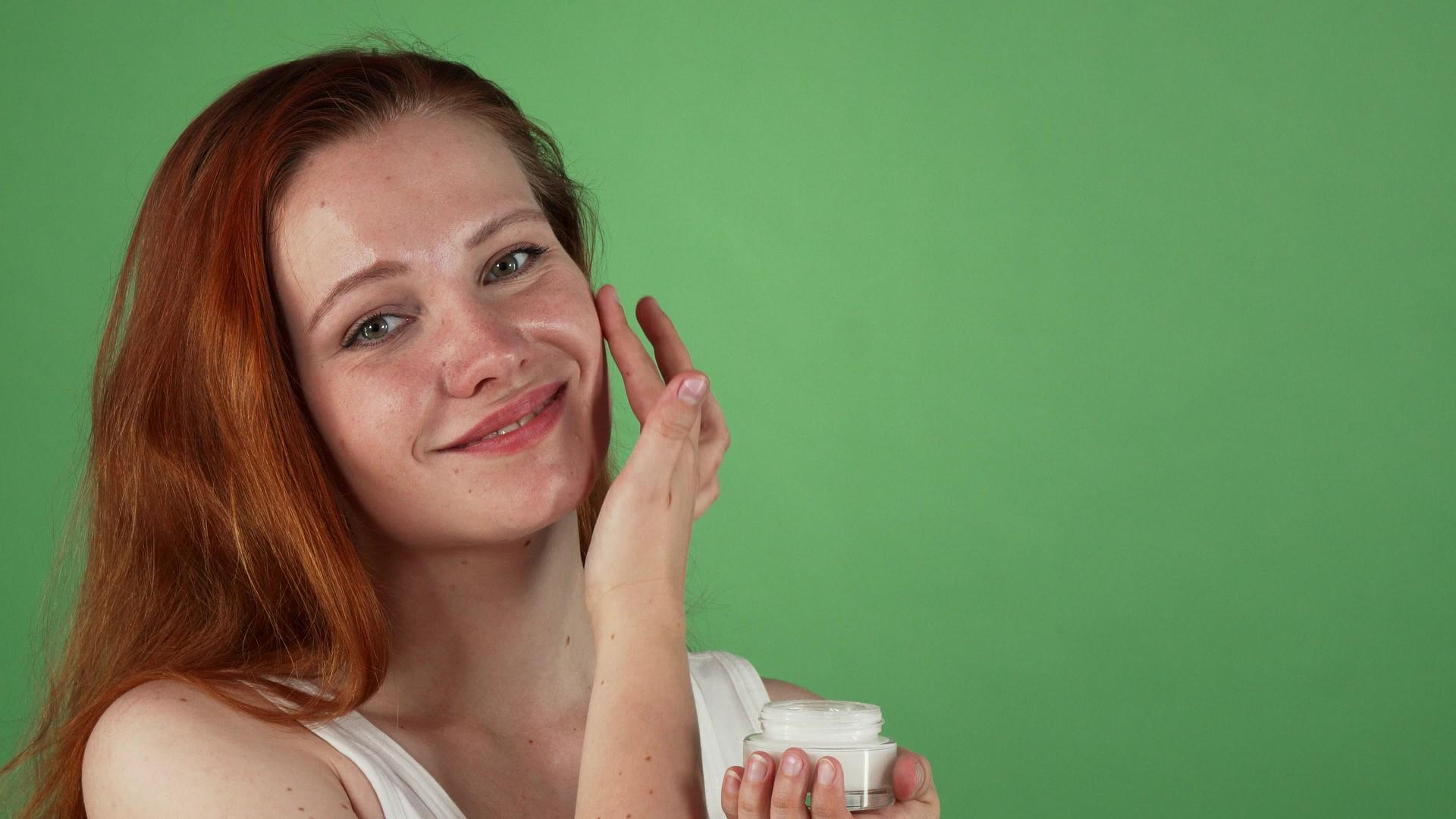 年轻迷人的红发美女使用面霜视频的预览图
