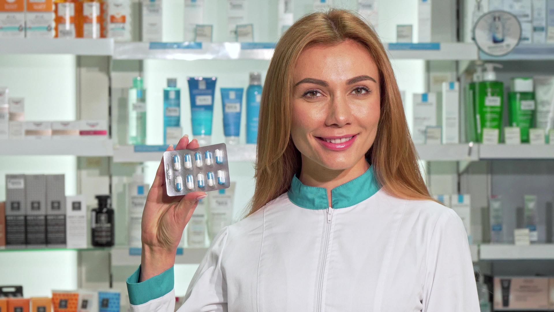 美丽的女药师微笑着在药店里拿着胶囊泡泡视频的预览图