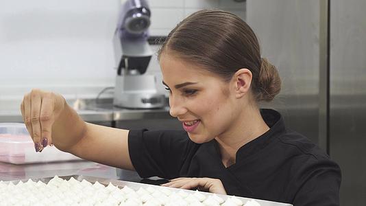 美丽的女性糕点厨师用椰子片蛋白环球装饰视频的预览图