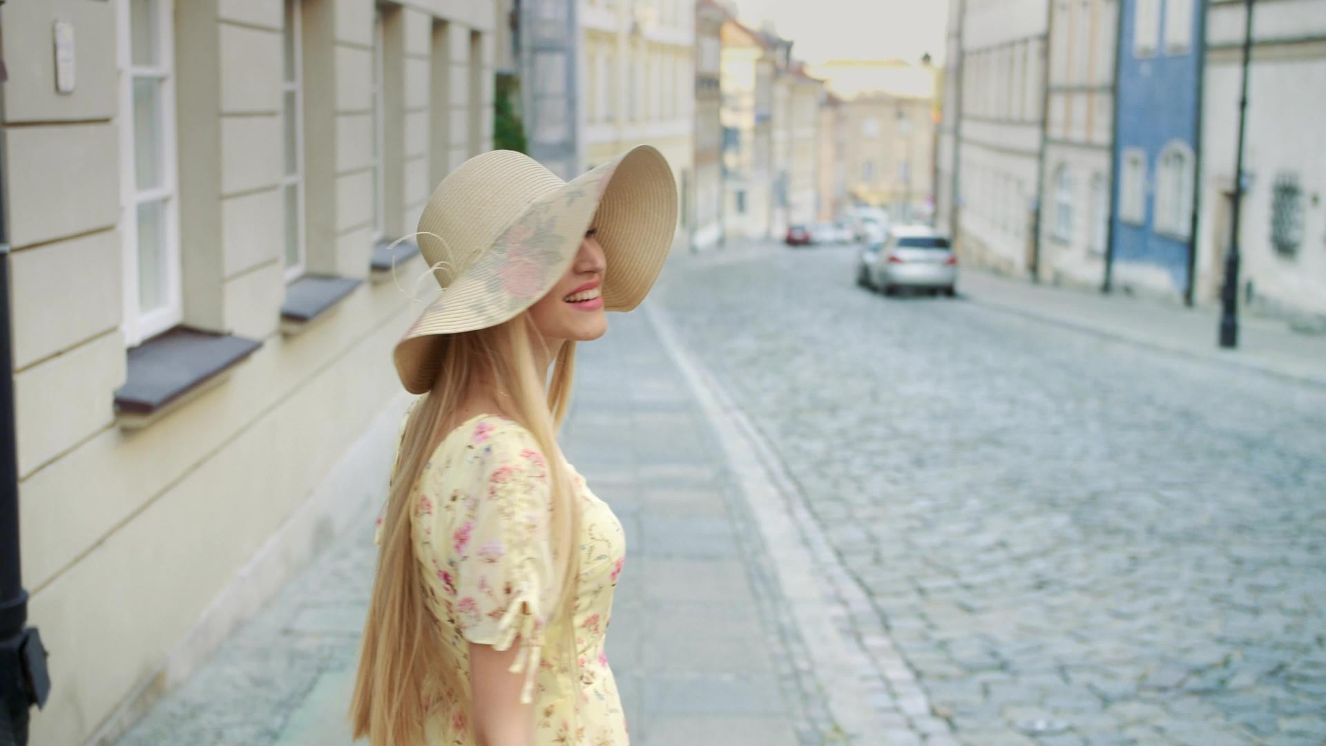 一个戴着白帽子的漂亮女孩走在城市里看着镜头笑得要死视频的预览图
