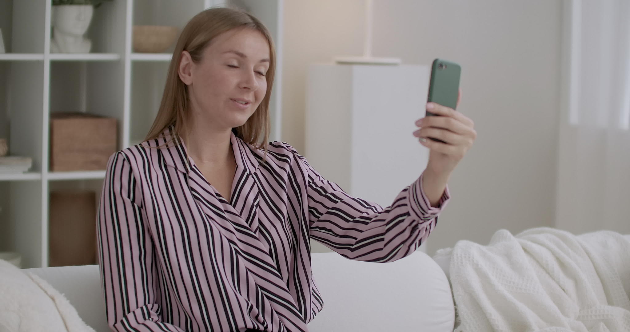 年轻女性用智能手机坐在家里视频的预览图