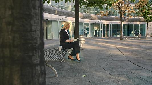 成功的商业女性在户外做笔记优雅的年轻女性坐在院子里视频的预览图
