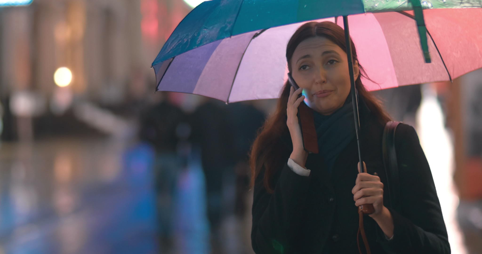 带着雨伞的年轻女子在电话里说话视频的预览图