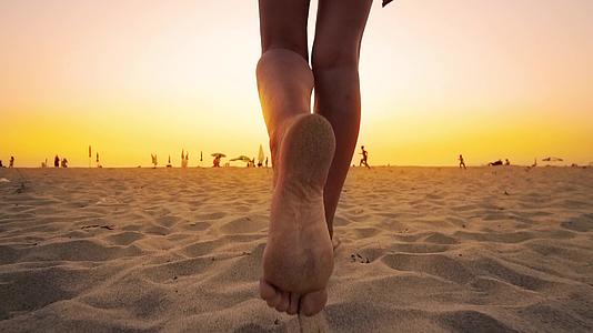日落时穿着比基尼的年轻女子在沙滩上慢慢地走着视频的预览图