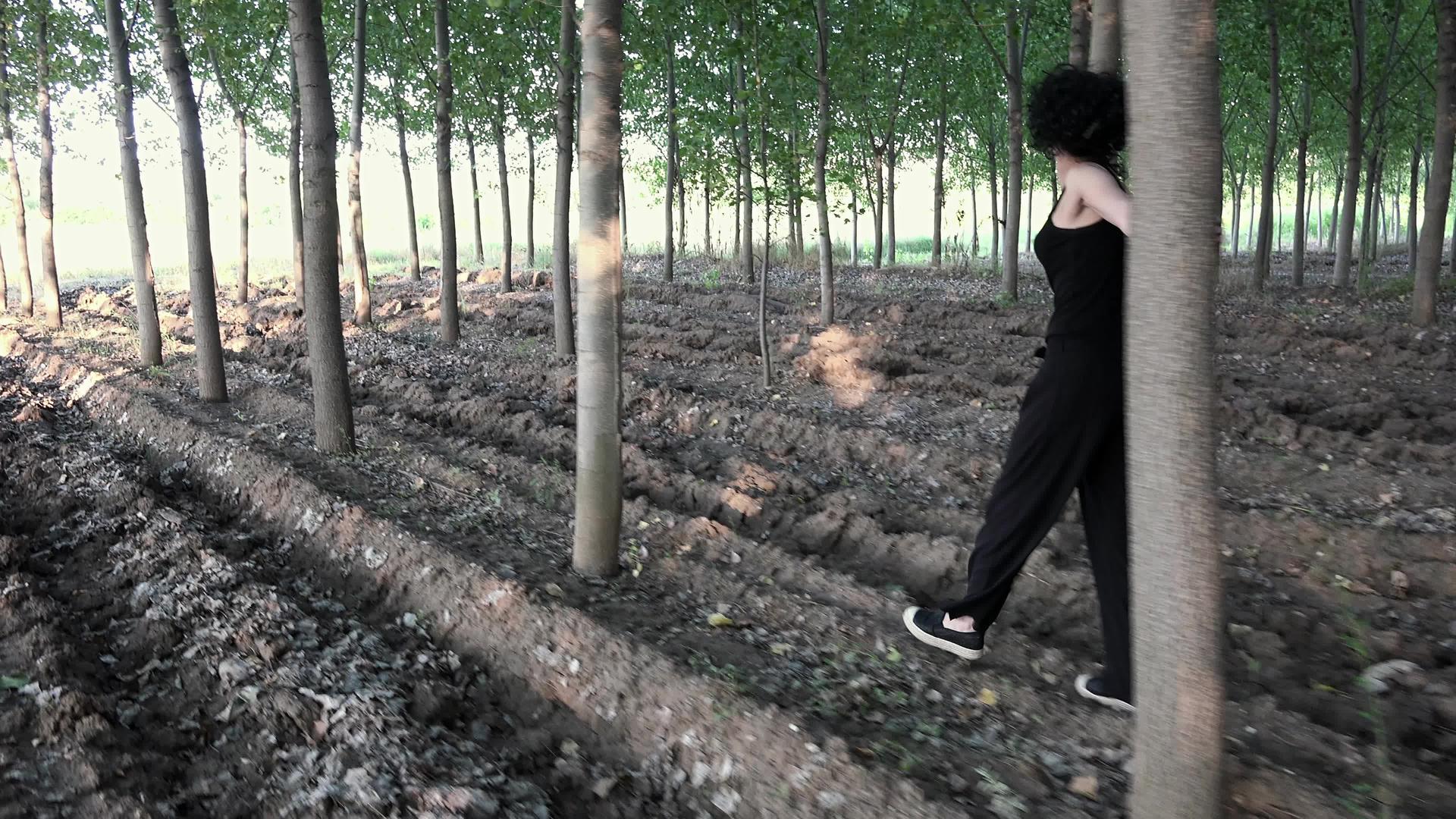 美丽的黑棕色美丽的女人走在茂美的树林里视频的预览图