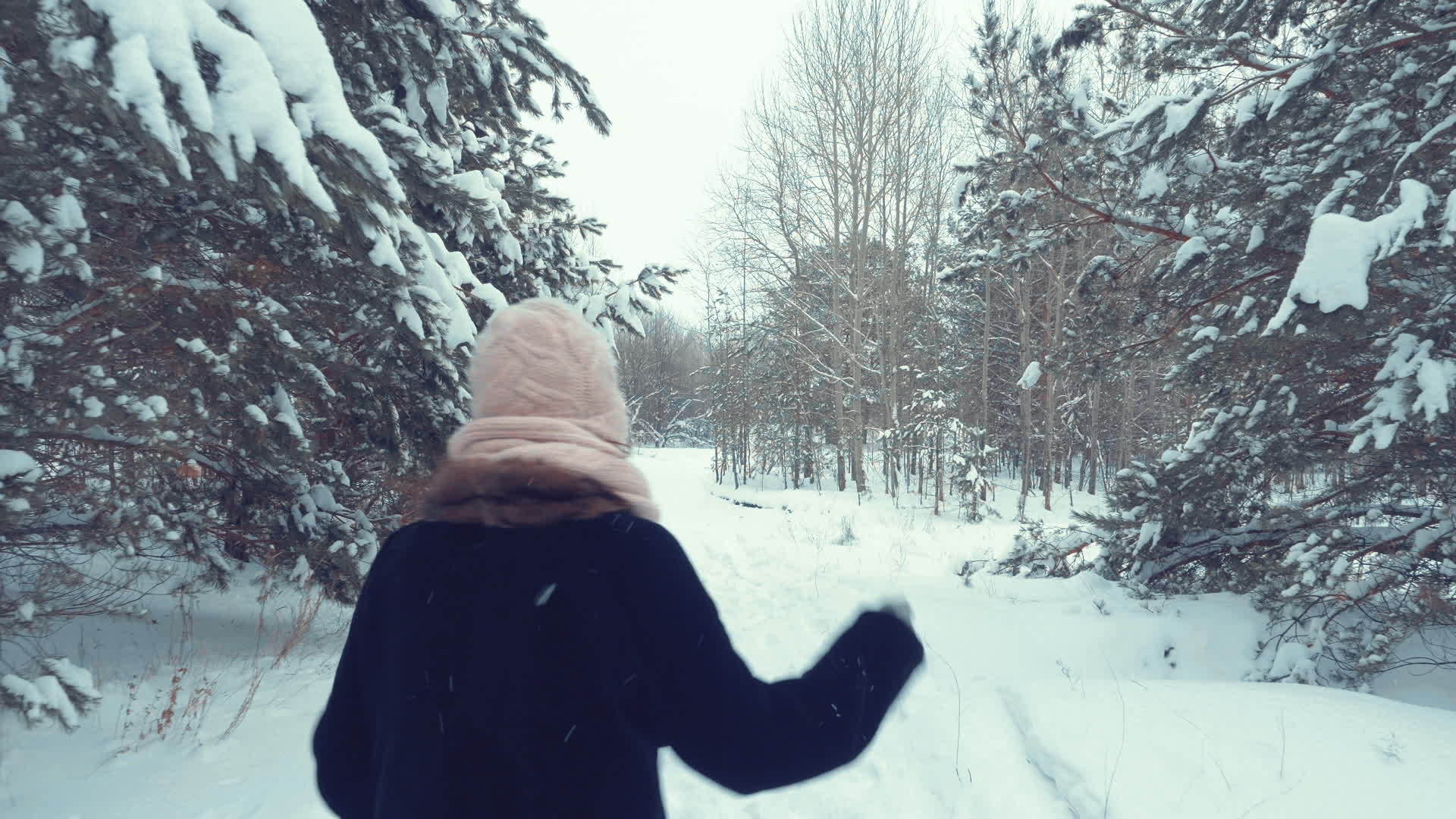 成年妇女在寒冷的一天享受在雪林中奔跑的无忧无虑视频的预览图
