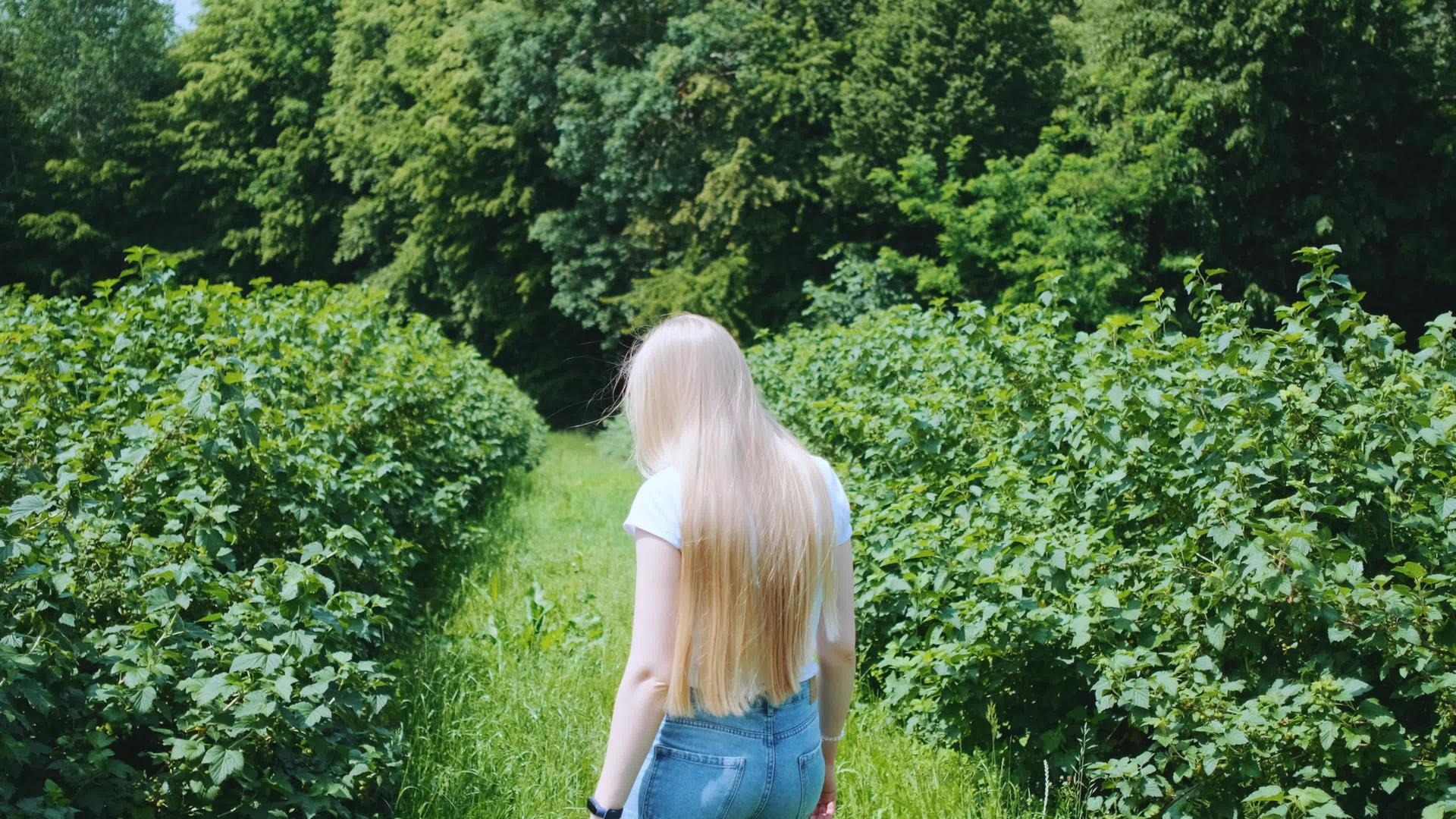 走在自然公园里的金发年轻女子视频的预览图
