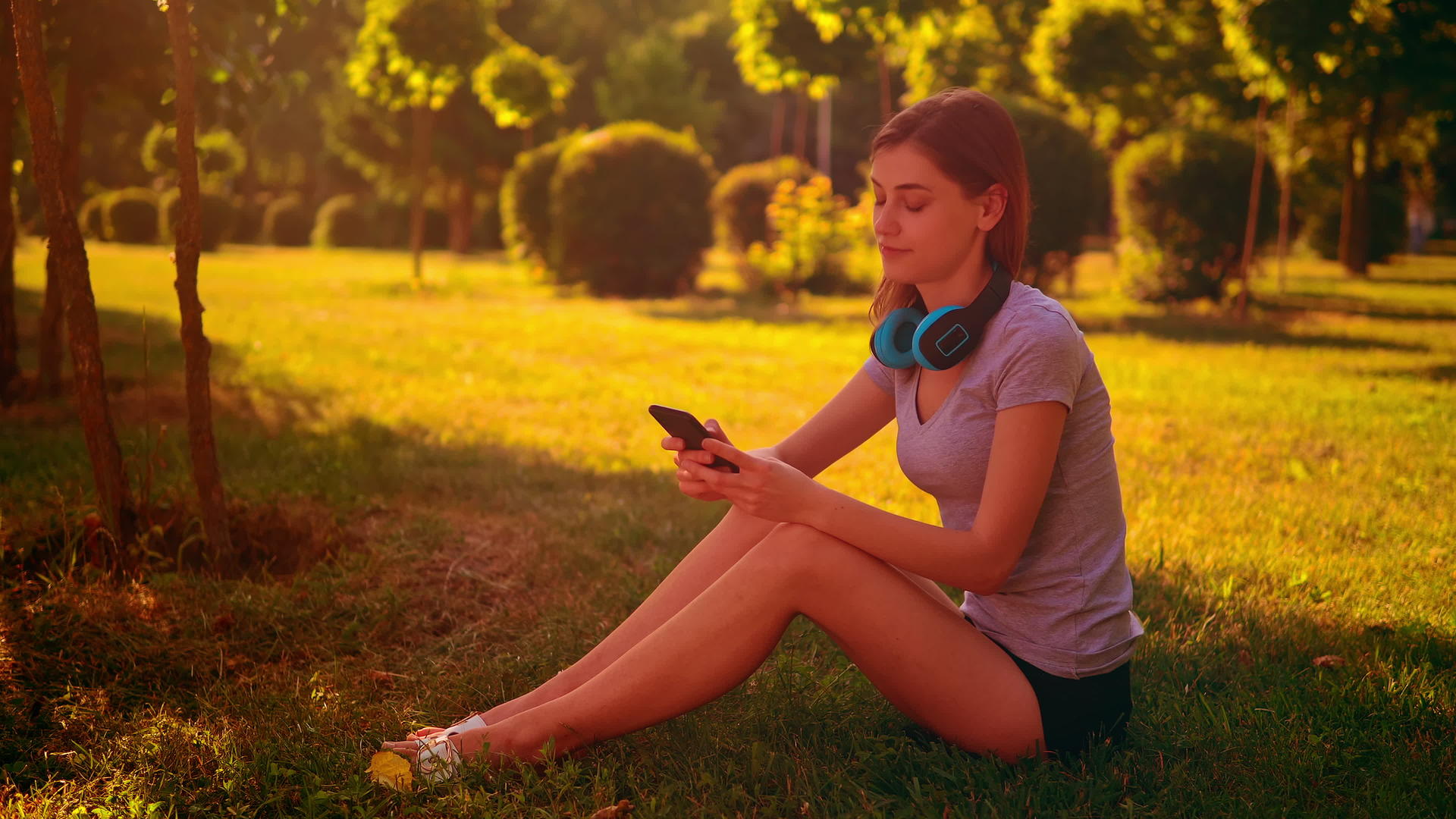 快乐地听音乐的女人坐在绿草地上视频的预览图