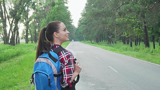 在乡村公路上行走欣赏大自然的幸福女性背包车视频的预览图