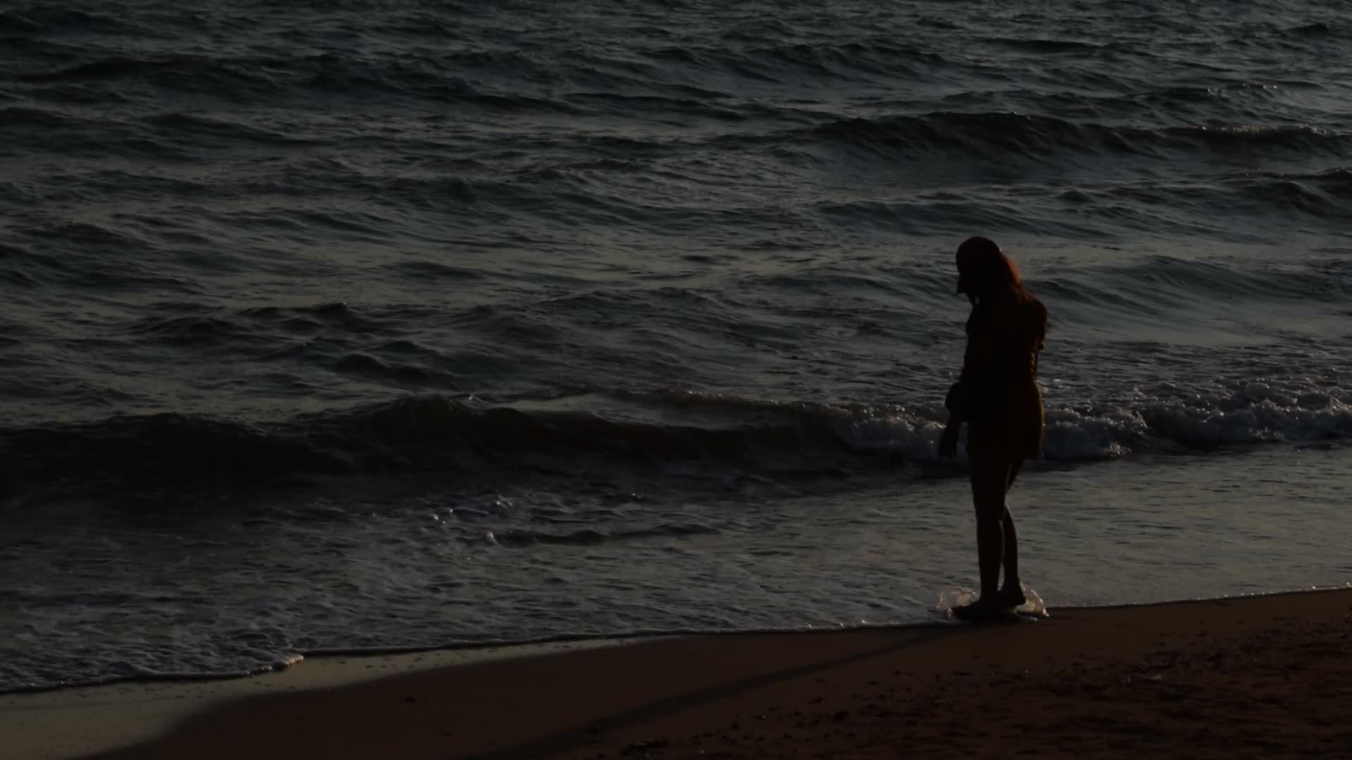 女人在海滩上行走的轮廓视频的预览图