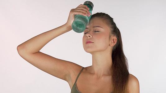 女运动员把水瓶放在额头上运动后休息视频的预览图