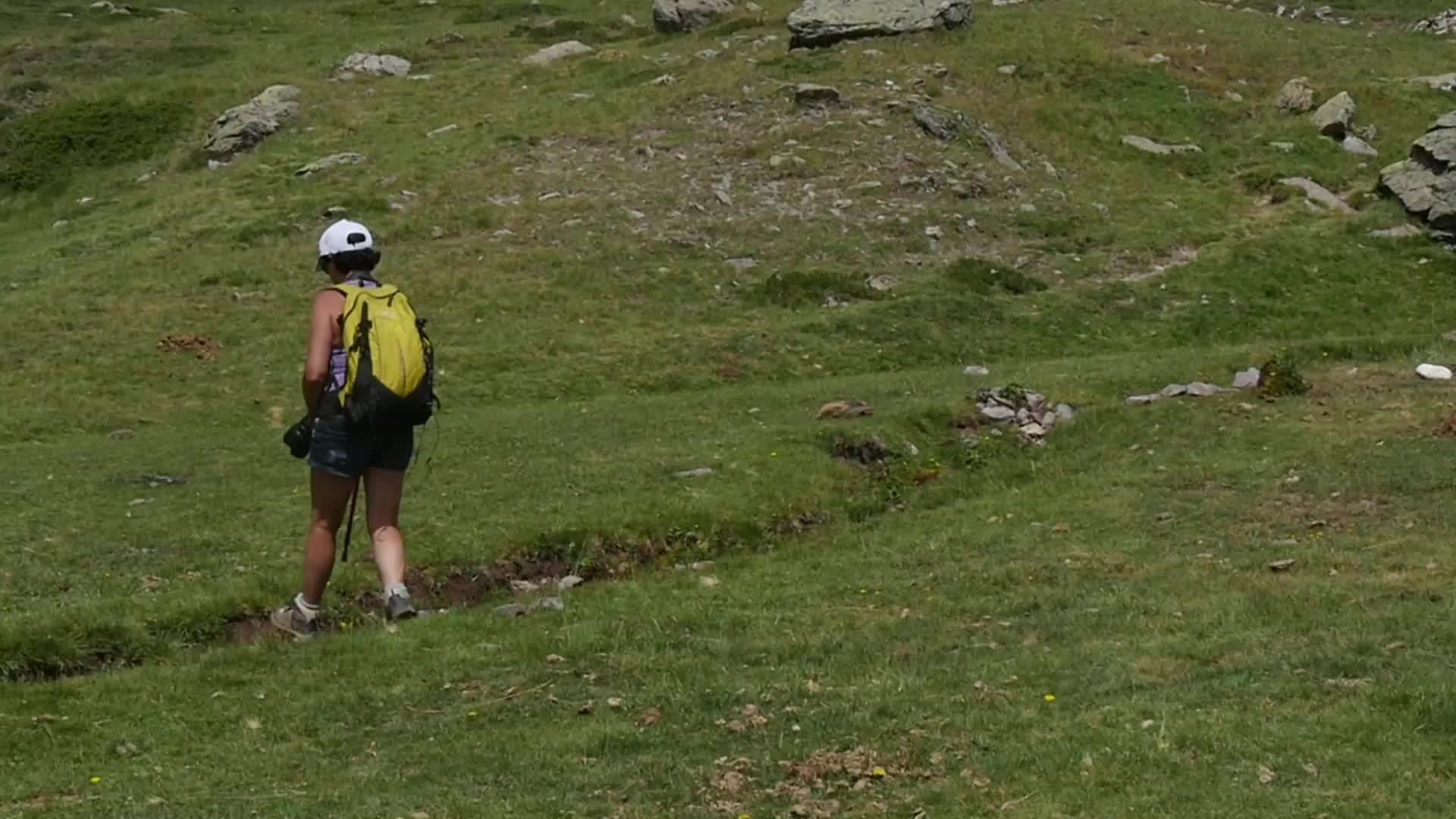 一个女人背着背包在山上慢慢地走着视频的预览图