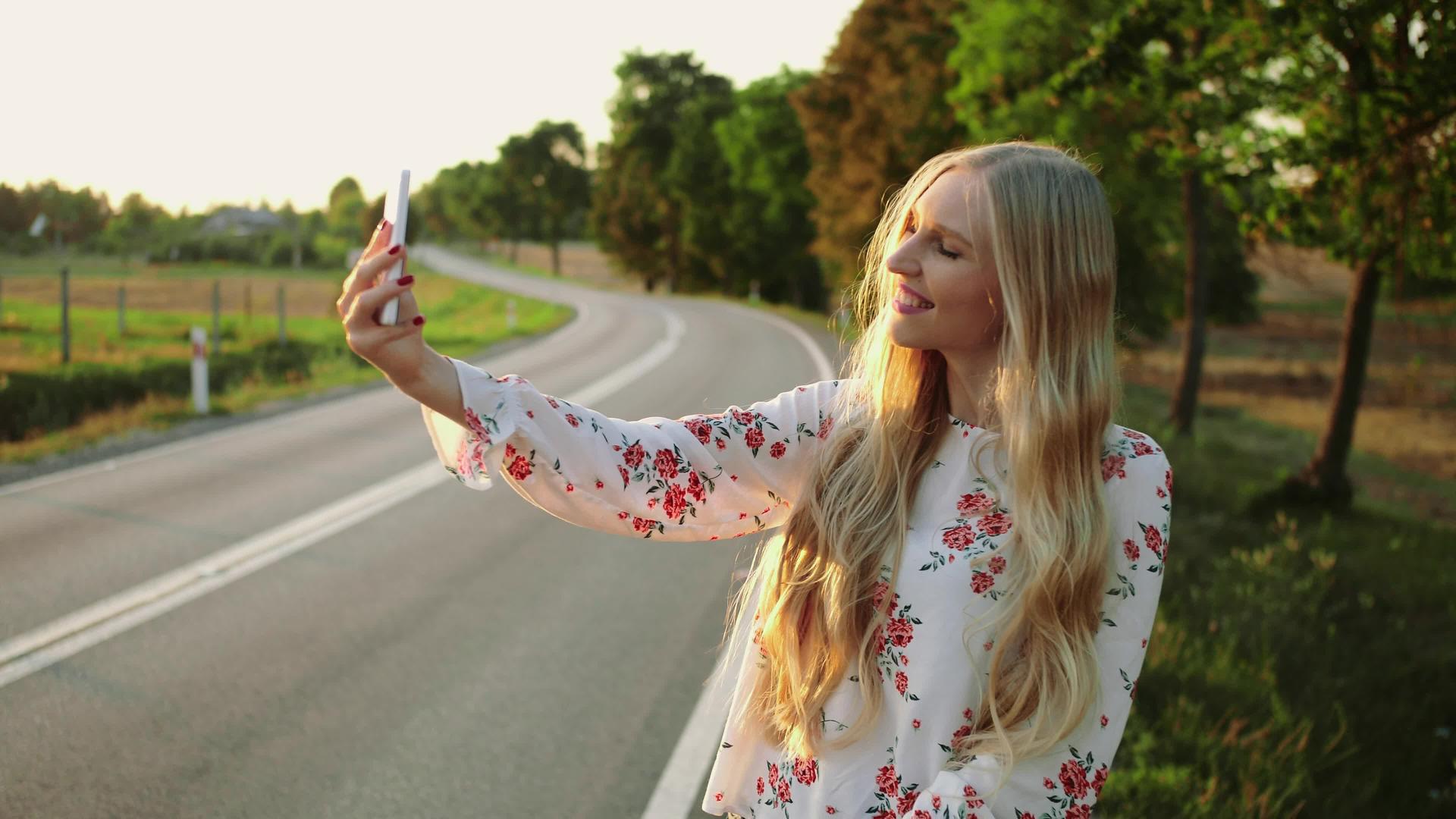 一名妇女在小路附近打视频电话年轻女士在欧洲农村搭便车视频的预览图