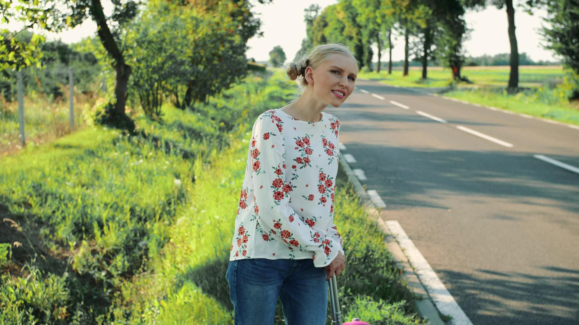 旅行者的年轻女子在农村道路上搭便车视频的预览图