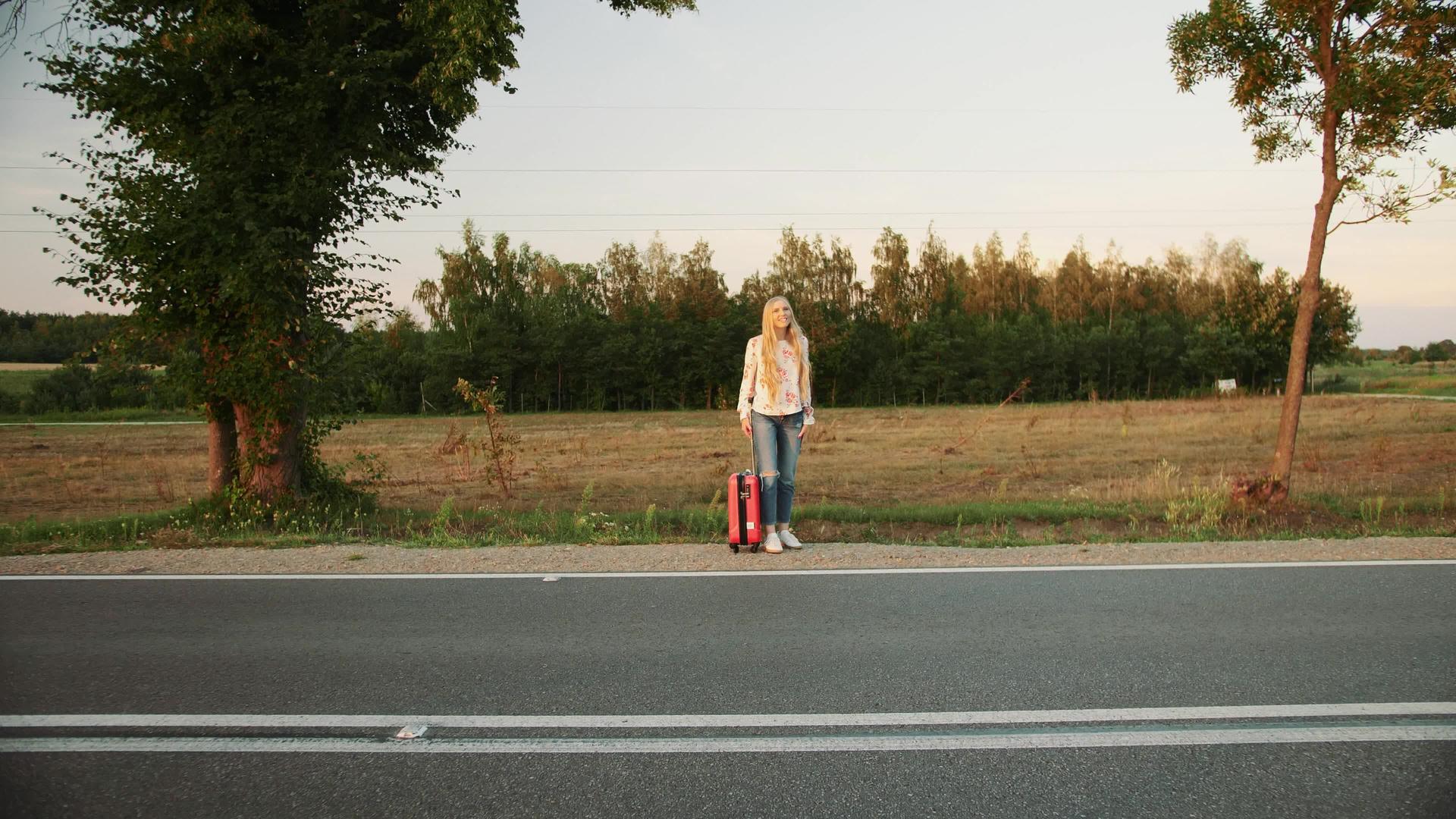 一个在农村路上搭便车的年轻女士视频的预览图