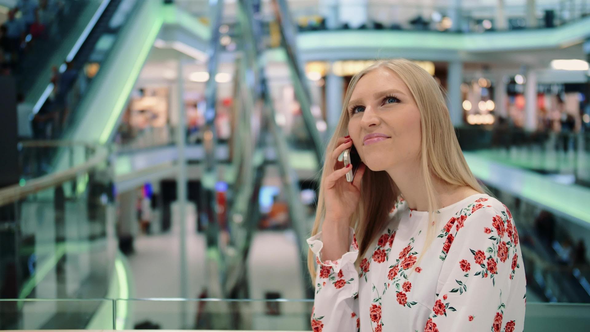 年轻女子在商场的电话里讲话视频的预览图
