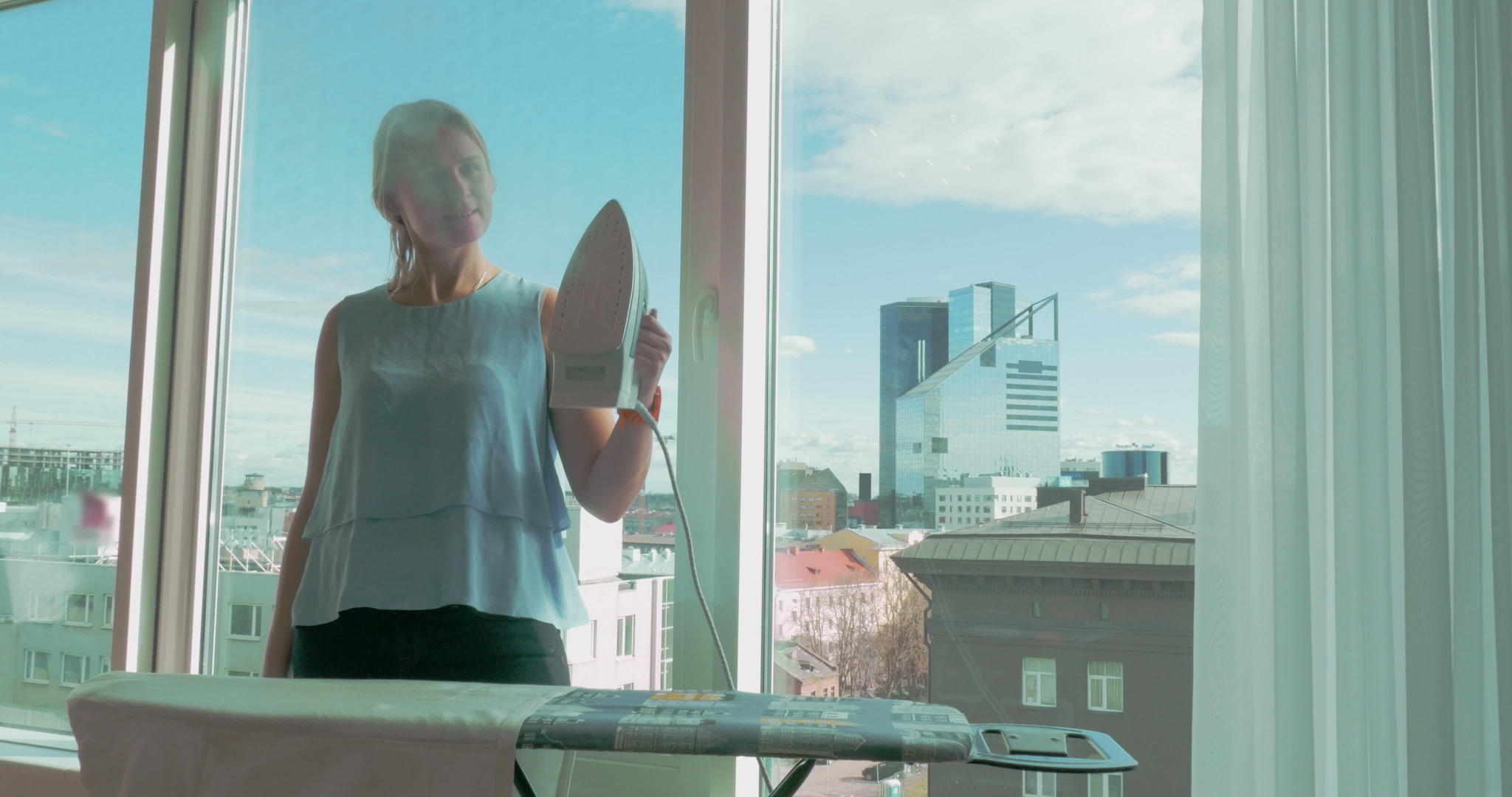 年轻女性在家用窗户熨衣服视频的预览图