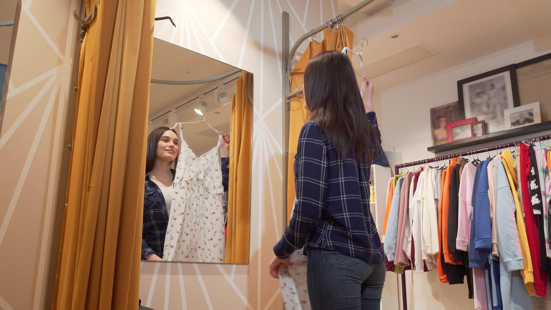 一位年轻美女在服装店试穿裙子的低角拍摄视频的预览图