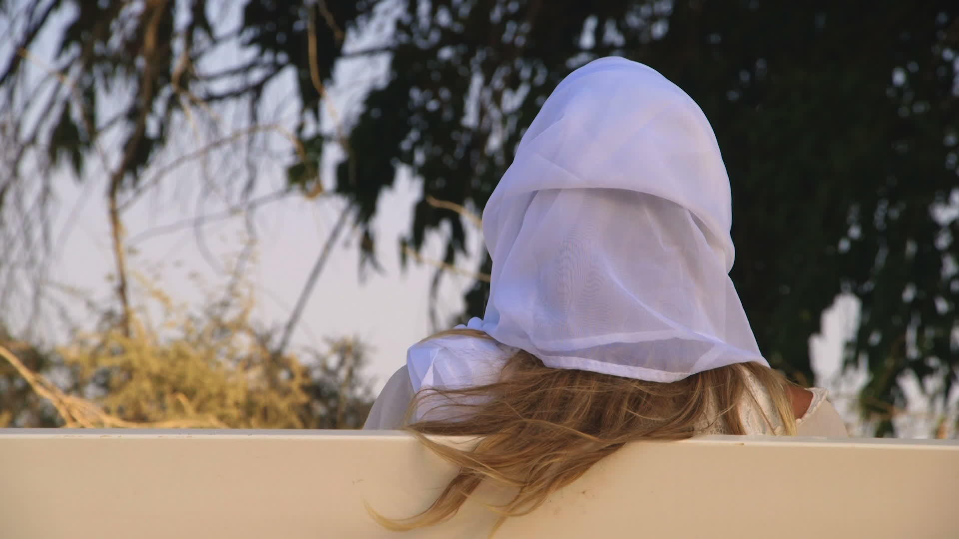 金发女子穿着白色裙子坐在长凳上视频的预览图