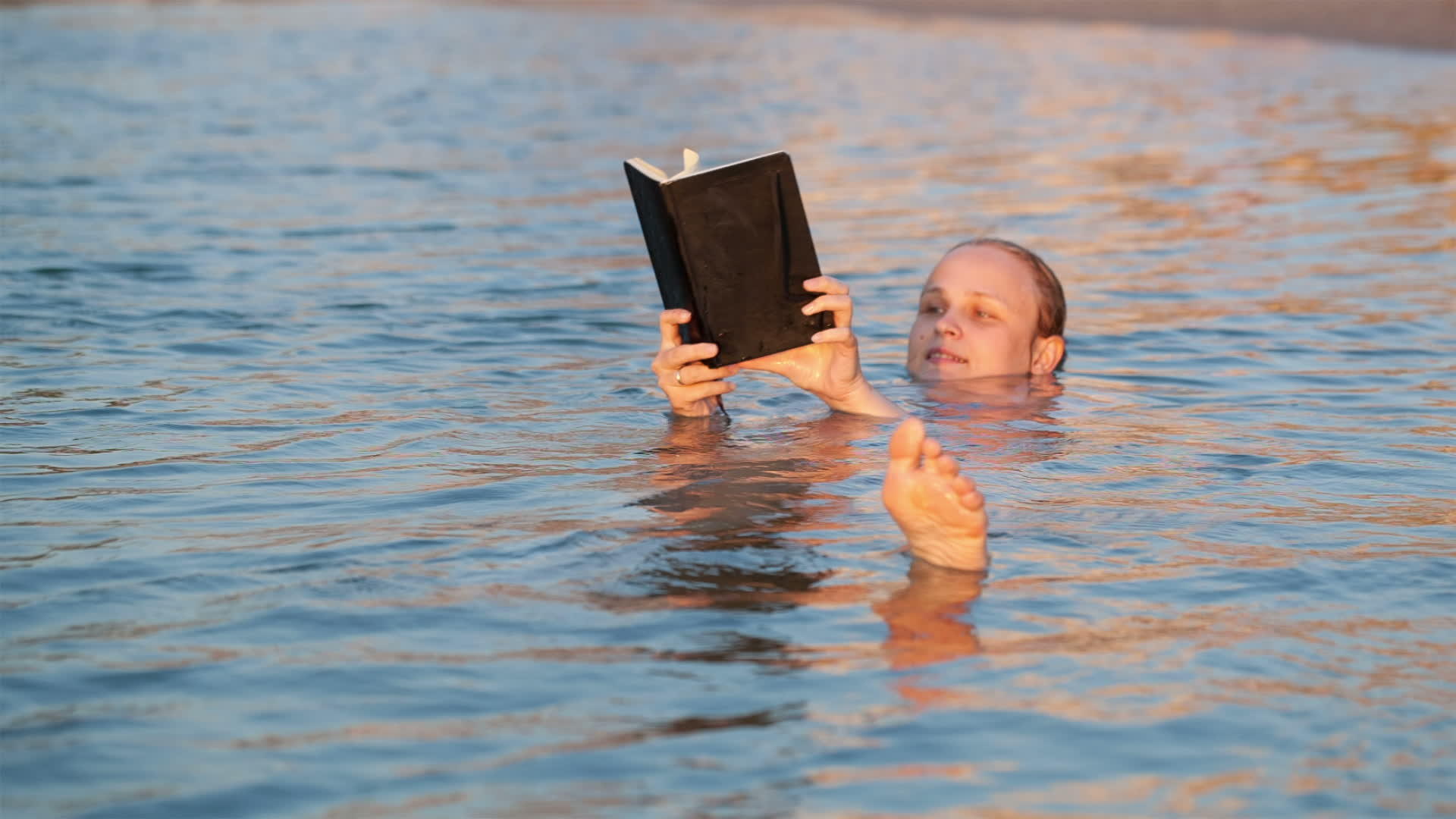 女人游泳时笑着看书视频的预览图