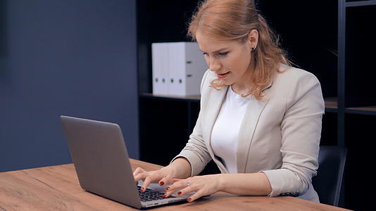 自信的中年女性专注于用笔记本电脑在桌子上工作视频的预览图