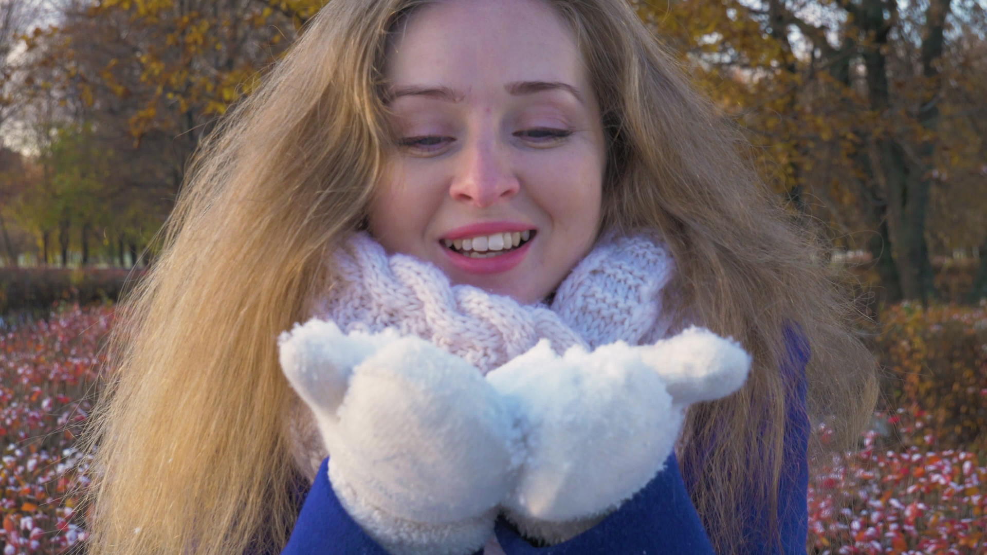在阳光明媚的白天穿着白手套的年轻美女在冬天吹雪视频的预览图