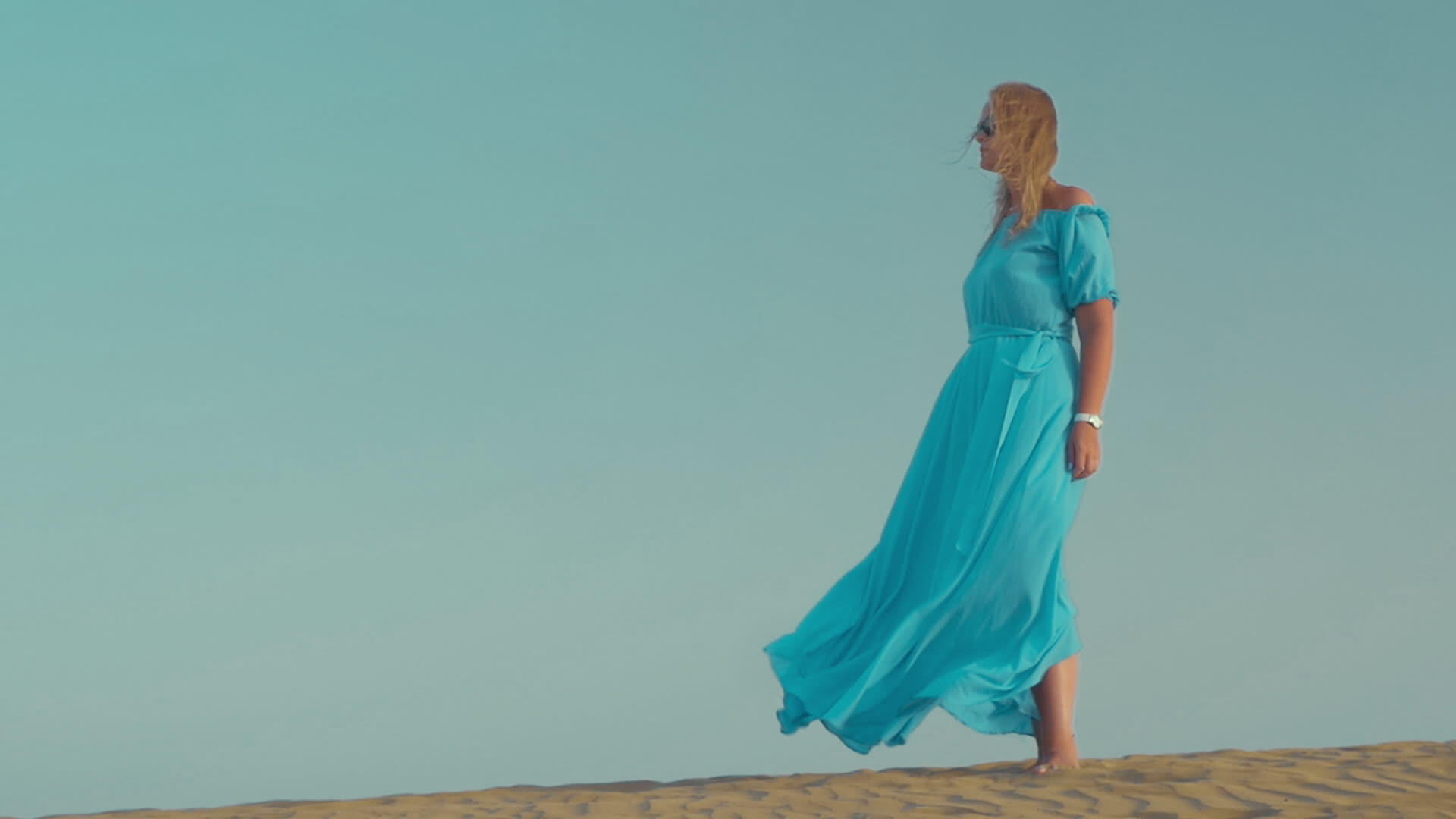 海滩上穿着蓝色裙子的女人视频的预览图