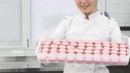 一位糕点厨师带着粉红色的桃子笑了拿着托盘被拍了下来视频的预览图