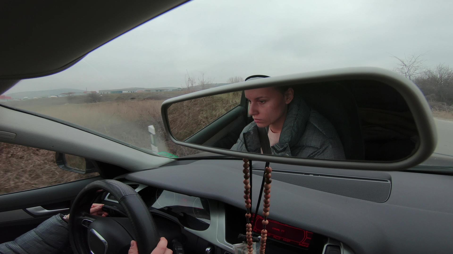 一个美丽的年轻女子在雾蒙蒙的路上驾驶汽车的后视镜视频的预览图