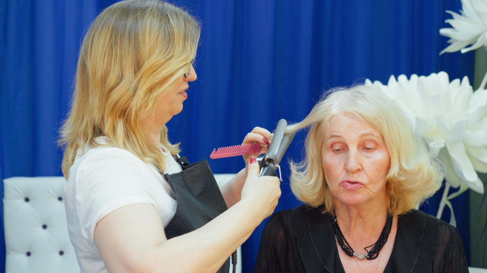 沙龙里的金发老太太做发型和理发师说话视频的预览图
