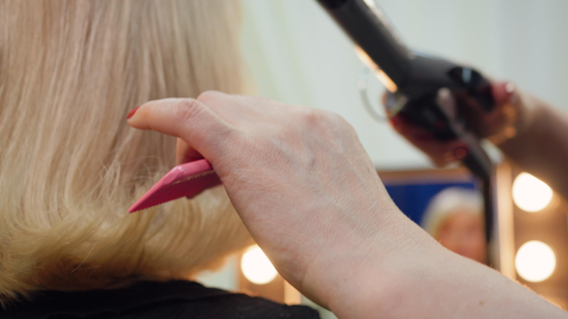 理发师的发型师正在给老年妇女做发型用铁手卷发视频的预览图