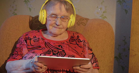现代祖母配备了平板电脑和耳机视频的预览图