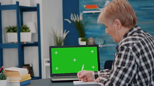 阅读绿色屏幕上的模拟铬键向老年人展示笔记本电脑视频的预览图