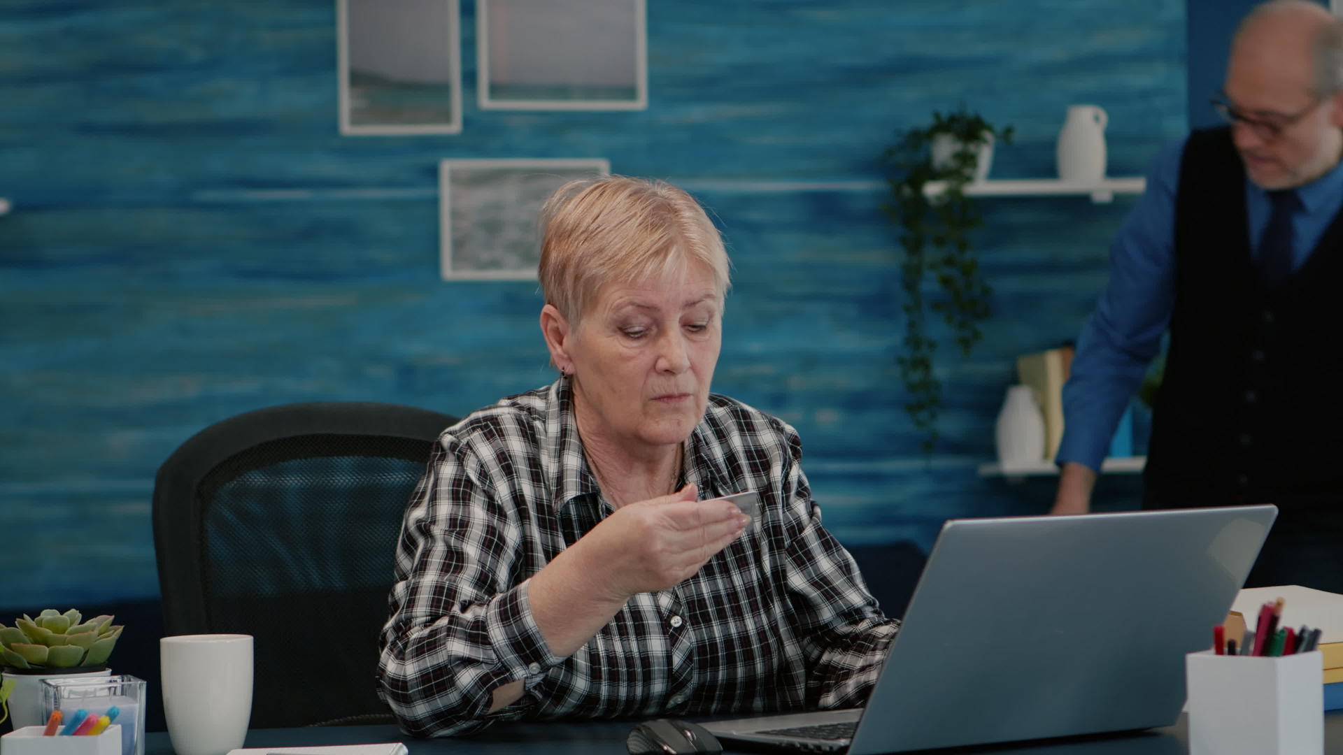 高级女性使用笔记本电脑信用卡在线支付视频的预览图