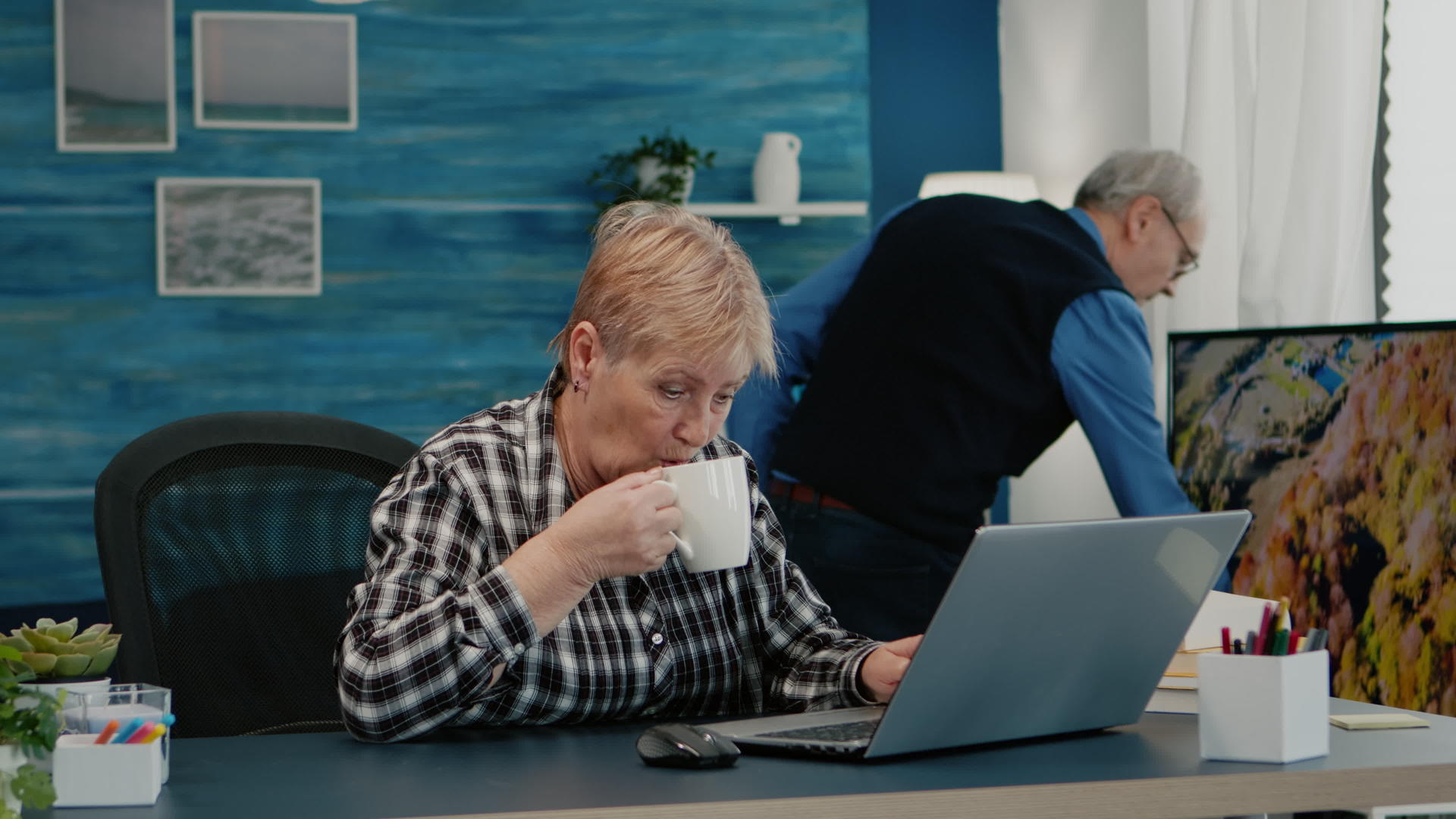 老年成年商业女性使用笔记本电脑坐在工作场所喝咖啡视频的预览图