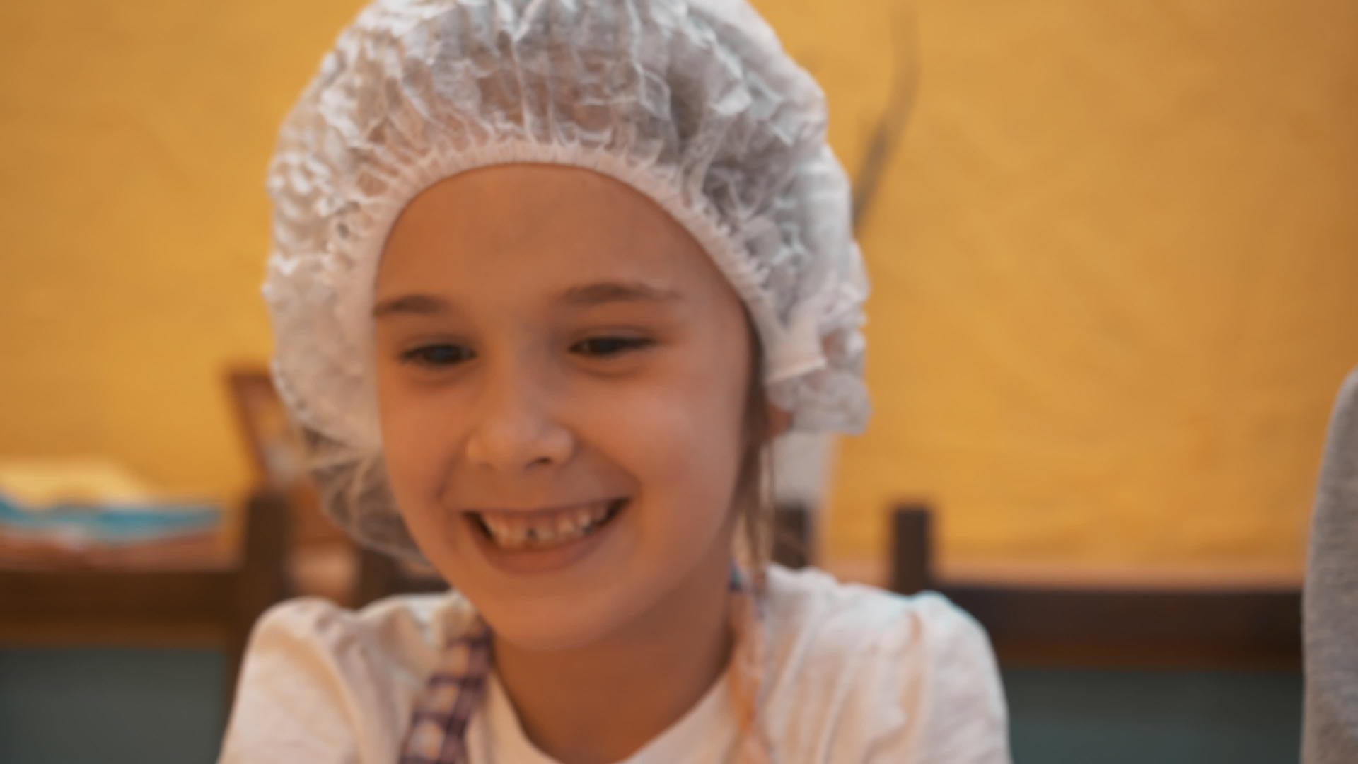 小女孩戴着一次性帽子在厨房里玩面团快乐的女孩正在做饭视频的预览图