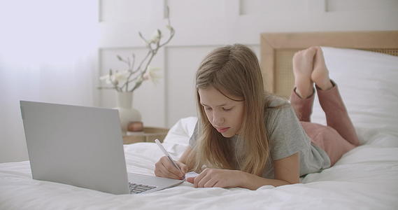 女学生在家里用笔记本电脑在线聊天在床上愉快地说话视频的预览图
