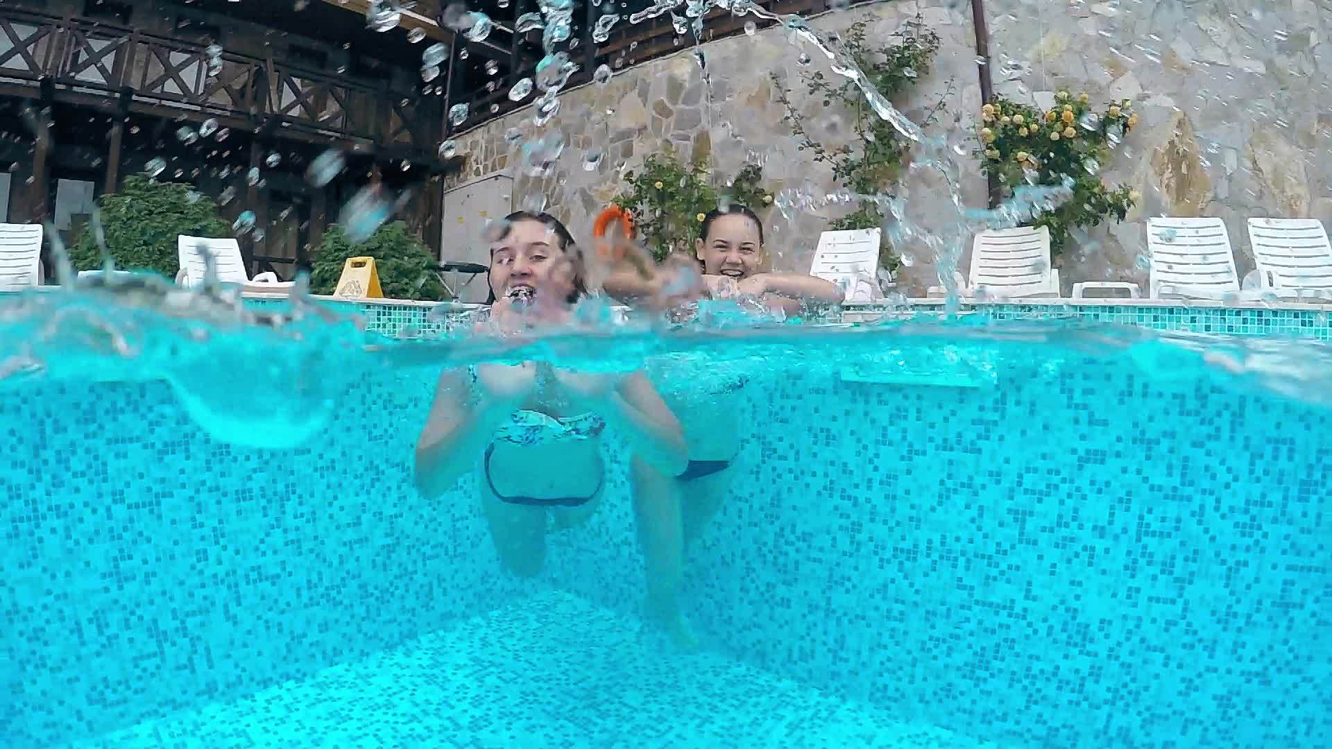 两个女青少年享受游泳池冲水相机欢笑和舞蹈花水下风景视频的预览图