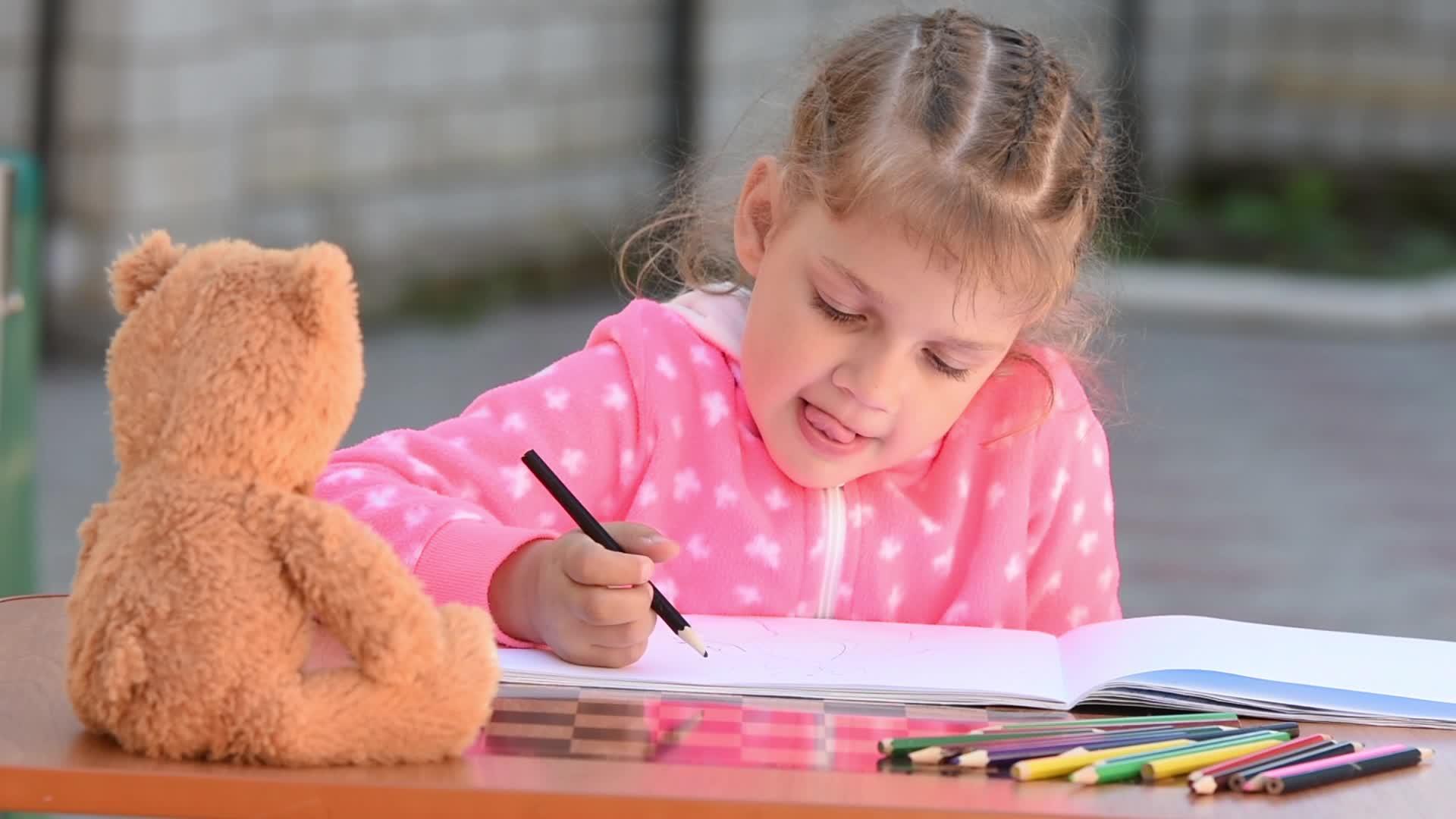 一个五岁的女孩热情地吸引了一只泰迪熊坐在她面前视频的预览图
