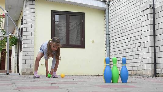 一名5岁女孩在院子里玩儿童保龄球视频的预览图