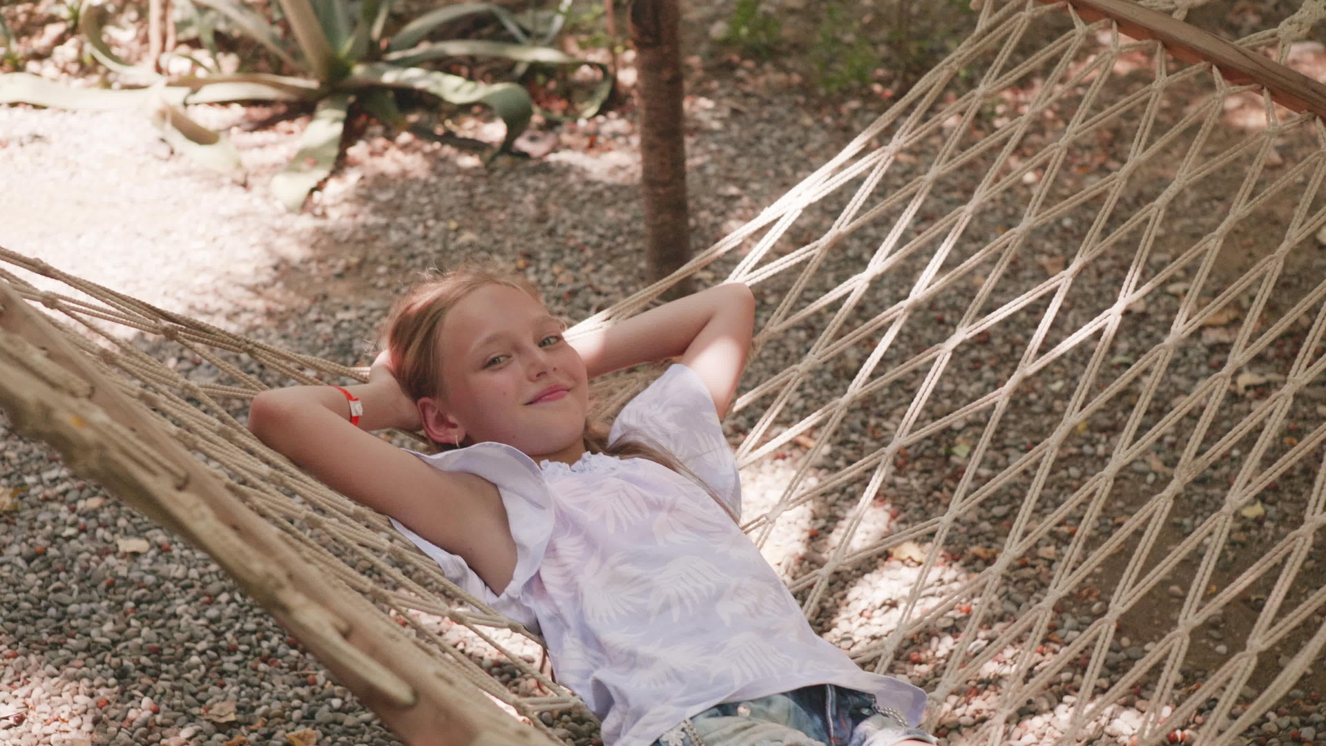 快乐的女孩在夏天躺在吊床上微笑女孩在暑假在吊床上微笑视频的预览图