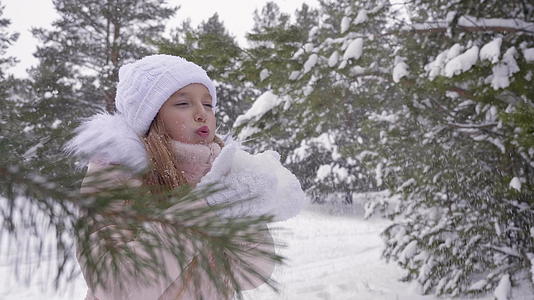 女孩从棕榈树上吹雪 把雪扔进森林 冬天下雪视频的预览图