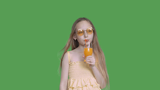 经过深思熟虑的女孩在假期喝橙汁透明的绿色背景笑声视频的预览图