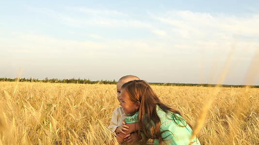 一个女孩抱着一个小男孩在小麦田里走来走去视频的预览图