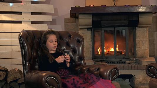 小女孩穿着漂亮的裙子晚上在家里用智能手机和朋友聊天视频的预览图