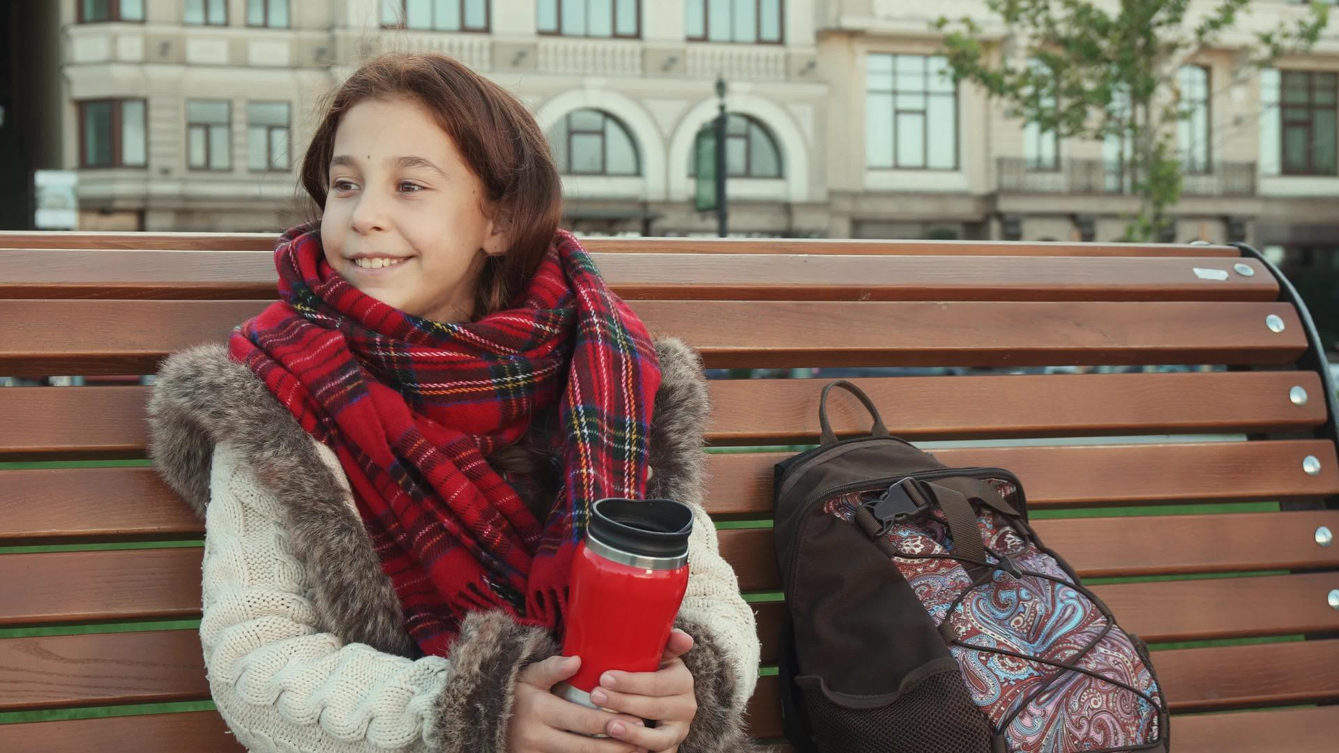 一个小女孩坐在大城市的长椅上视频的预览图
