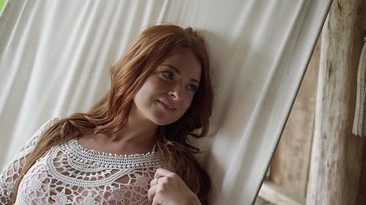 一个穿着透明轻薄衣服的年轻女孩躺在吊床上红发美女视频的预览图