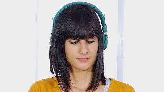 年轻女性戴着性戴着绿色耳机听音乐慢动作视频的预览图